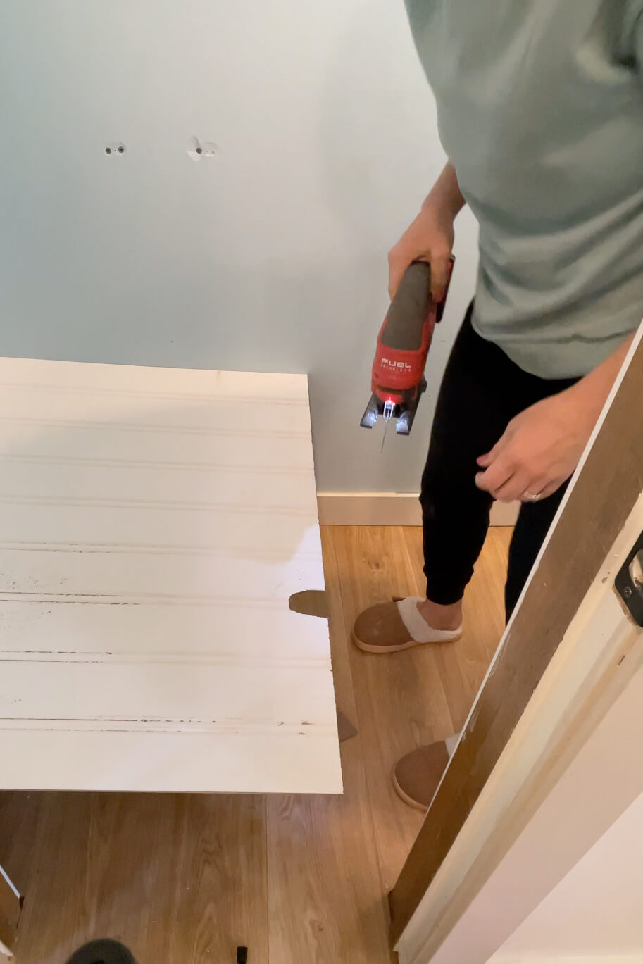 Using a jigsaw to cut a hole for the bathroom plumbing in a piece of beadboard.